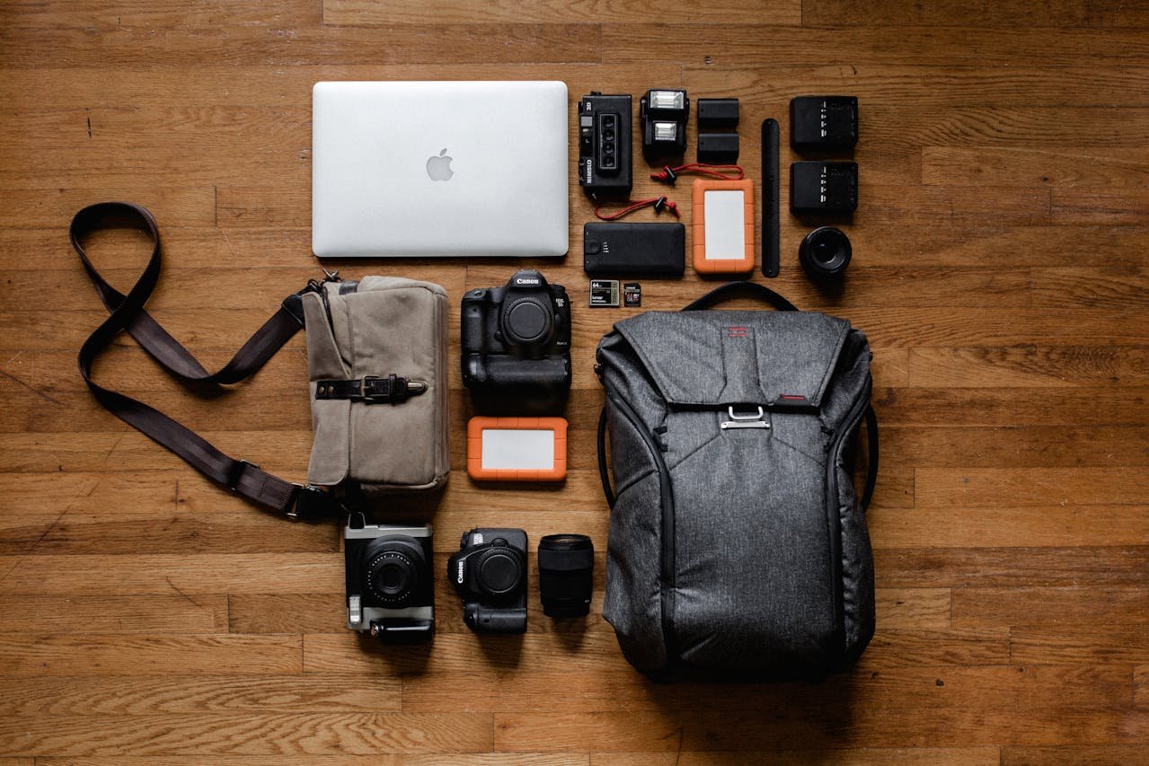 Flachgelegte Ausrüstung des Fotografen, einschließlich Kameras, Laptop und Rucksack.