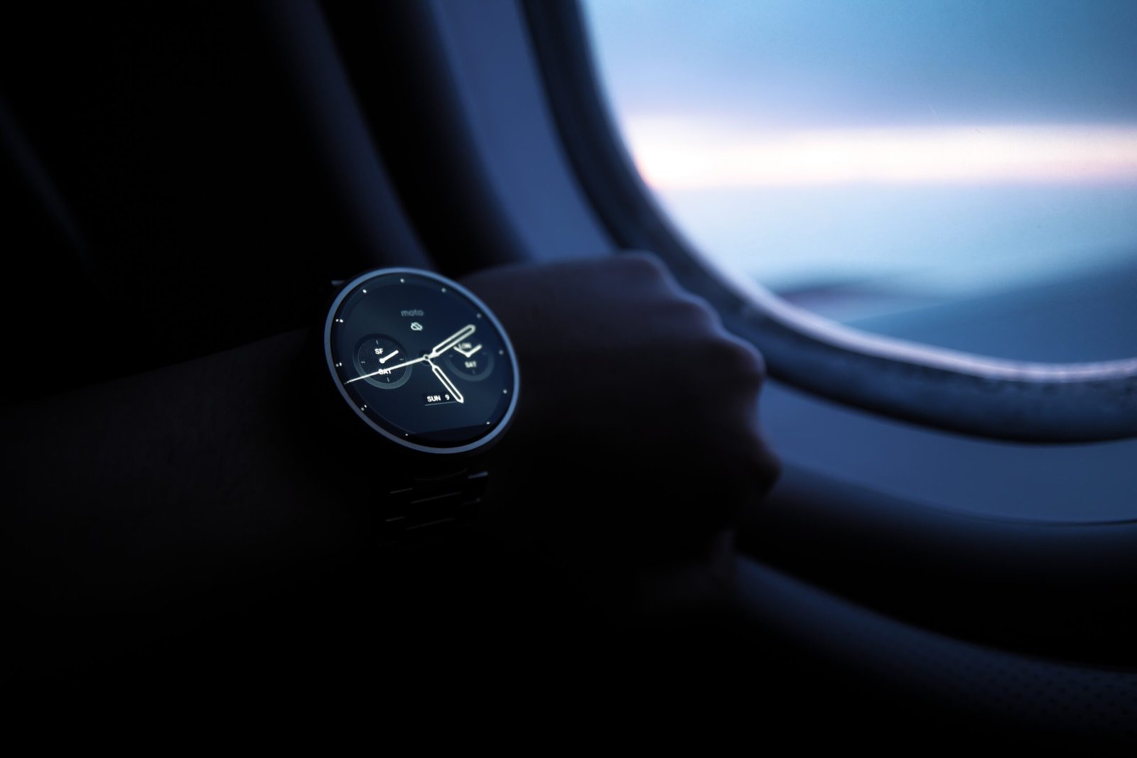 Person, die während des Sonnenuntergangs eine Moto 360-Smartwatch am Handgelenk trägt, von der Seite betrachtet.